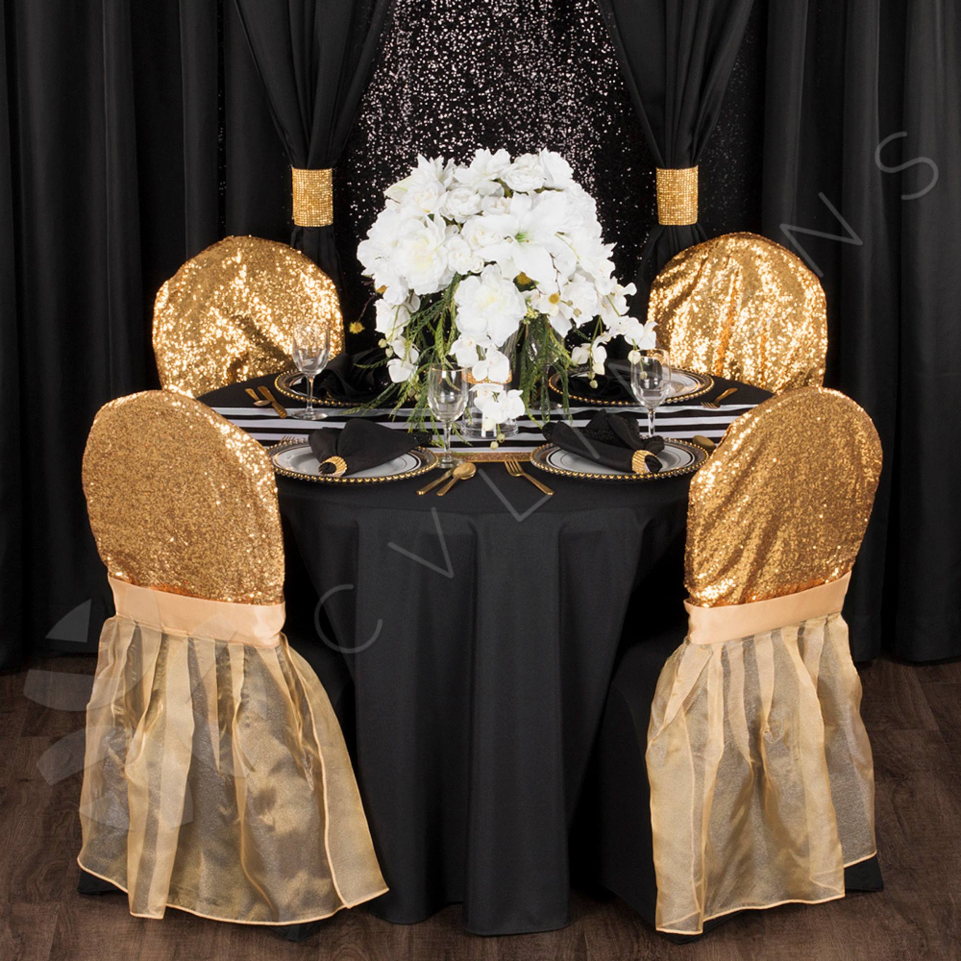 large gold rhinestone drape clips on black drapes behind a black, white, and gold tablescape